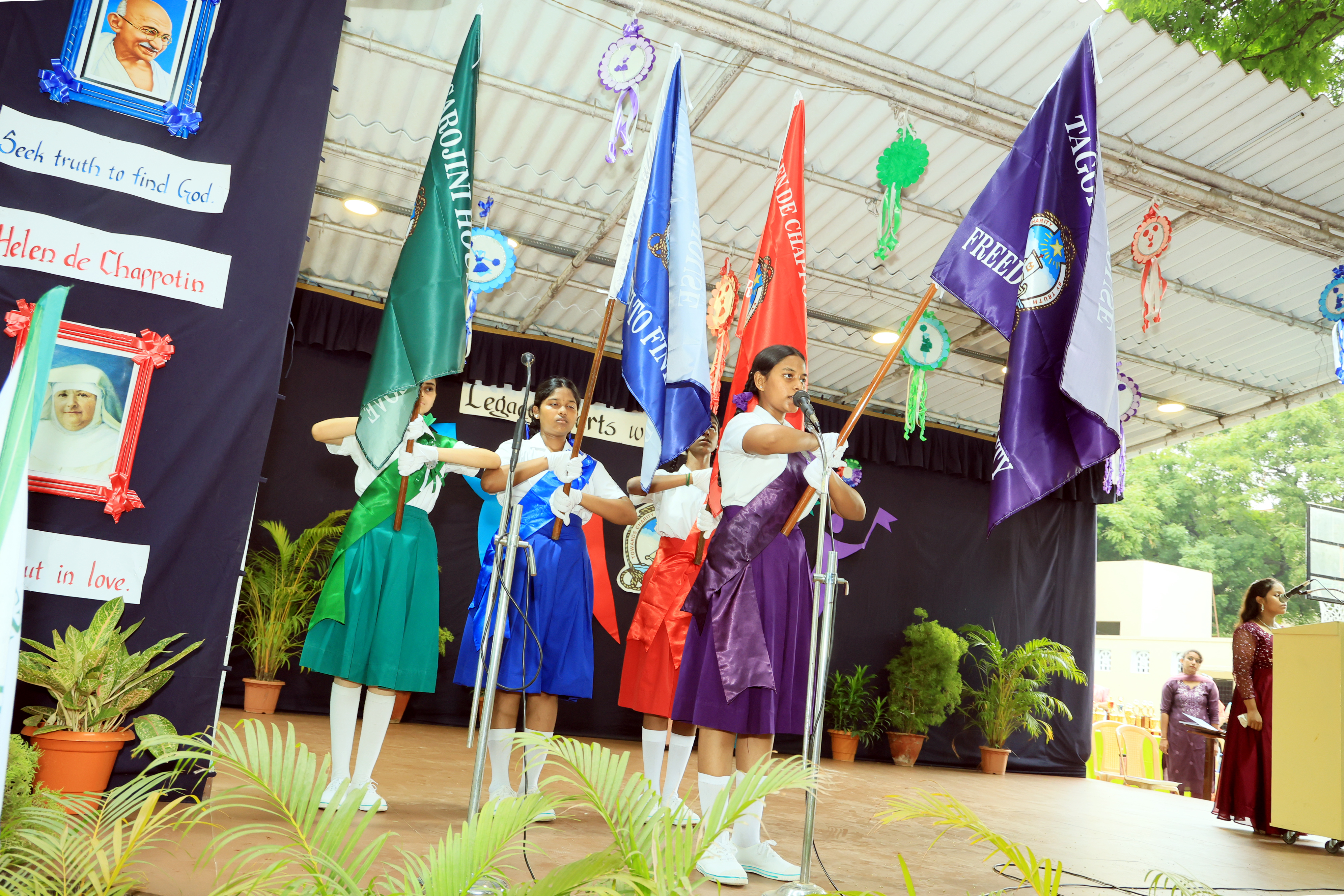 Students holding house flags on stage